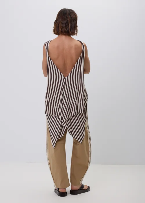 Damski top bez rękawów w beżowo-brązowe paski o luźnym, asymetrycznym fasonie. Modna stylizacja casual ze spodniami w kolorze camel z ozdobnym koronkowym lampasem, inspirowana naturalną elegancją.