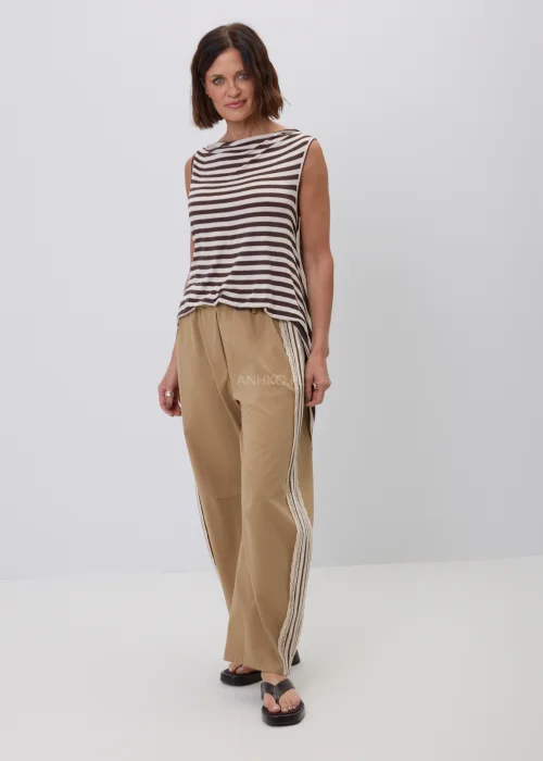 Damski top bez rękawów w beżowo-brązowe paski o luźnym, asymetrycznym fasonie. Modna stylizacja casual ze spodniami w kolorze camel z ozdobnym koronkowym lampasem, inspirowana naturalną elegancją.