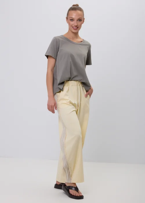 Szary damski T-shirt oversize o luźnym, lekko rozkloszowanym fasonie z krótkim rękawem i okrągłym dekoltem. Minimalistyczna bluzka basic w stonowanym odcieniu, zestawiona z jasnymi spodniami w eleganckiej codziennej stylizacji.