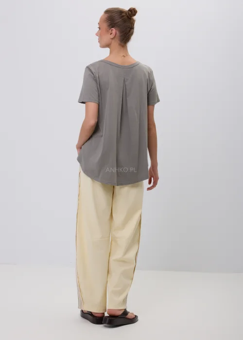 Szary damski T-shirt oversize o luźnym, lekko rozkloszowanym fasonie z krótkim rękawem i okrągłym dekoltem. Minimalistyczna bluzka basic w stonowanym odcieniu, zestawiona z jasnymi spodniami w eleganckiej codziennej stylizacji.