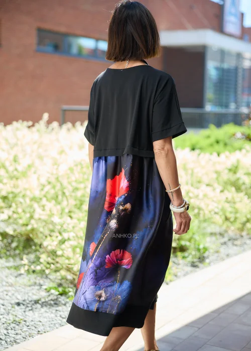 Czarna sukienka midi damska z efektownym nadrukiem czerwonych maków na granatowym tle, o luźnym fasonie i krótkich rękawach. Elegancka stylizacja z ozdobnym naszyjnikiem i bordowymi czółenkami.