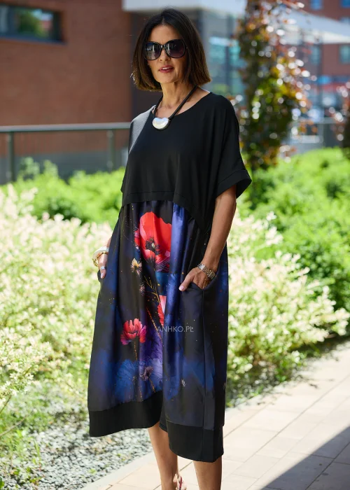 Czarna sukienka midi damska z efektownym nadrukiem czerwonych maków na granatowym tle, o luźnym fasonie i krótkich rękawach. Elegancka stylizacja z ozdobnym naszyjnikiem i bordowymi czółenkami.