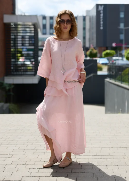 Pudroworóżowa lniana bluzka damska z rękawem 3/4, asymetrycznymi falbanami i luźnym fasonem oversize, prezentowana w eleganckiej miejskiej stylizacji.