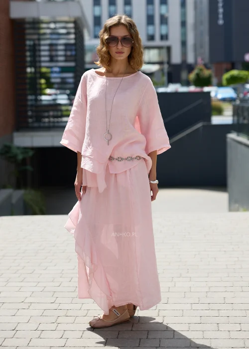 Pudroworóżowa lniana bluzka damska z rękawem 3/4, asymetrycznymi falbanami i luźnym fasonem oversize, prezentowana w eleganckiej miejskiej stylizacji.