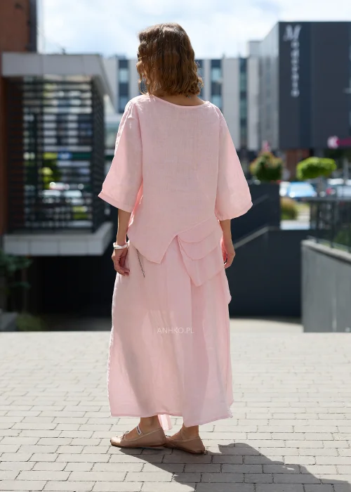 Pudroworóżowa lniana bluzka damska z rękawem 3/4, asymetrycznymi falbanami i luźnym fasonem oversize, prezentowana w eleganckiej miejskiej stylizacji.