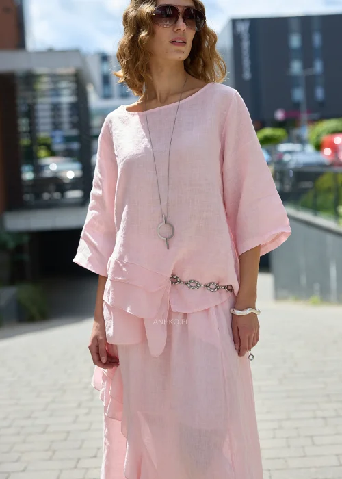 Pudroworóżowa lniana bluzka damska z rękawem 3/4, asymetrycznymi falbanami i luźnym fasonem oversize, prezentowana w eleganckiej miejskiej stylizacji.