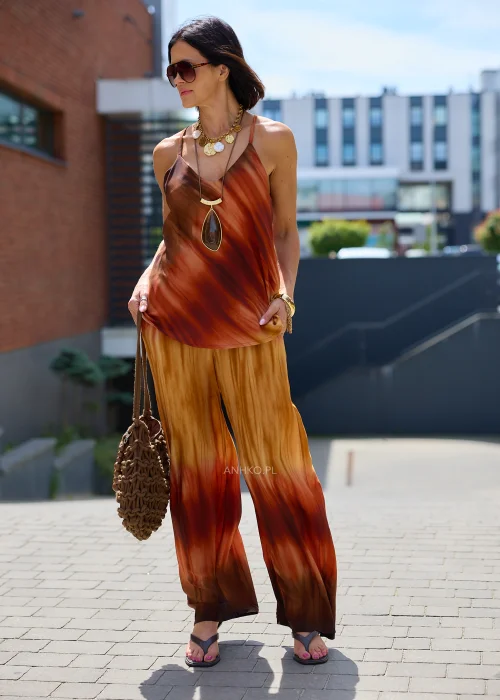Zwiewne spodnie palazzo z efektem ombre w odcieniach karmelu, miedzi i ciemnego brązu. Szerokie nogawki oraz lekko kreszowana tkanina nadają modelowi elegancki, płynny wygląd idealny do stylizacji boho i resort.