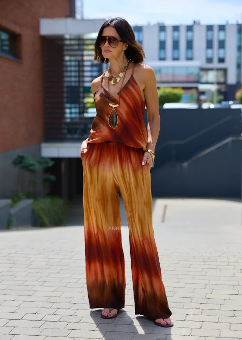 Zwiewne spodnie palazzo z efektem ombre w odcieniach karmelu, miedzi i ciemnego brązu. Szerokie nogawki oraz lekko kreszowana tkanina nadają modelowi elegancki, płynny wygląd idealny do stylizacji boho i resort.