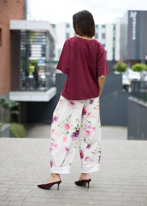 Kremowe spodnie w kwiatowy print z szeroką nogawką i elastyczną talią. Lekki model w różowo-fioletowe kwiaty idealny do romantycznych i kobiecych stylizacji.