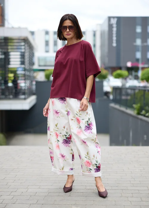 Kremowe spodnie w kwiatowy print z szeroką nogawką i elastyczną talią. Lekki model w różowo-fioletowe kwiaty idealny do romantycznych i kobiecych stylizacji.