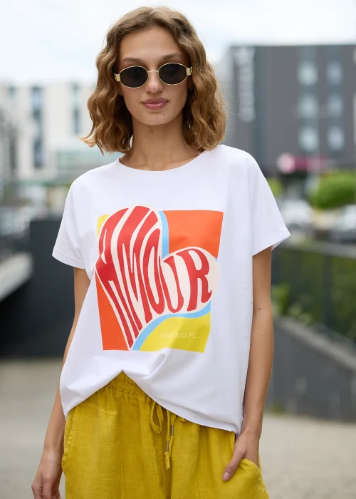 Biały t-shirt z kolorowym nadrukiem kowbojskich botków wypełnionych kwiatami na różowym tle.