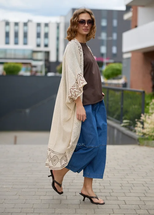 Kimono boho ecru z geometrycznym wzorem w odcieniach beżu. Długi, luźny fason z lekkiej dzianiny tworzy efektowną warstwową stylizację