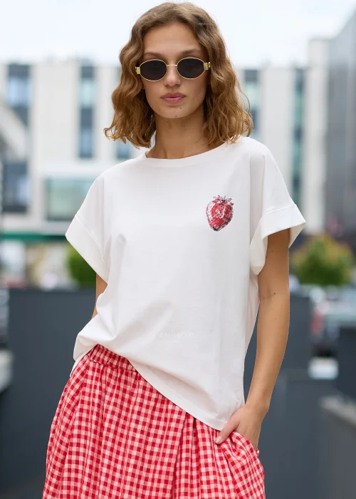Biały t-shirt o luźnym fasonie z podwiniętymi rękawami i subtelnym nadrukiem truskawki na piersi.