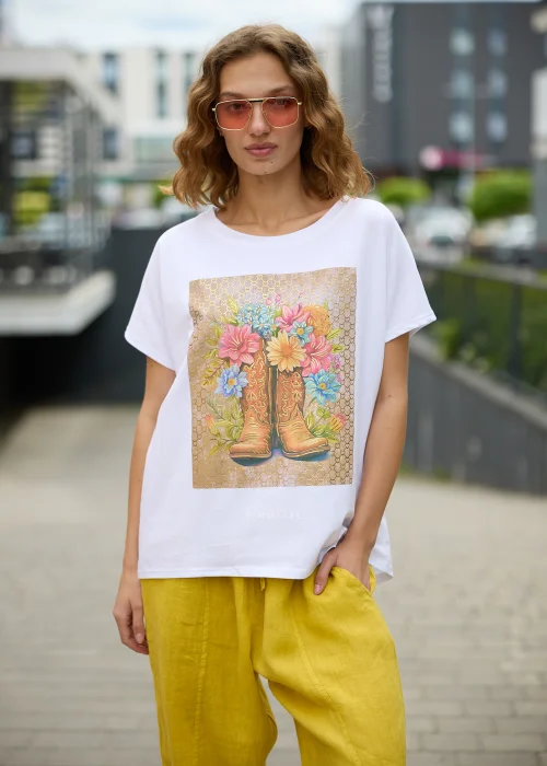 Biały t-shirt damski z efektownym nadrukiem kowbojskich botków wypełnionych kolorowymi kwiatami na beżowym tle.