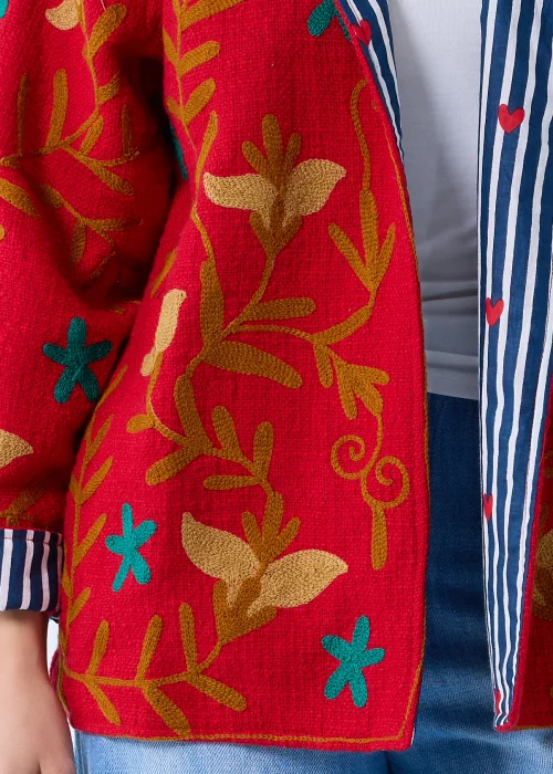 Czerwona pikowana kurtka damska z haftowanym roślinnym wzorem w odcieniach złota i turkusu, z kołnierzem oraz kontrastową podszewką w granatowo-białe paski
