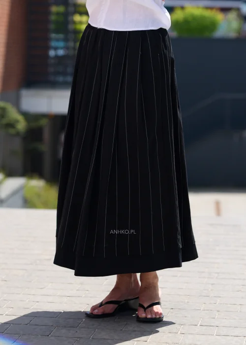 Czarna spódnica maxi z delikatnymi pionowymi prążkami i elastyczną talią, zwiewny fason w eleganckiej minimalistycznej stylizacji.