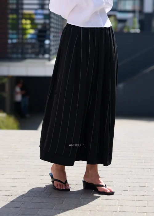 Czarna spódnica maxi z delikatnymi pionowymi prążkami i elastyczną talią, zwiewny fason w eleganckiej minimalistycznej stylizacji.