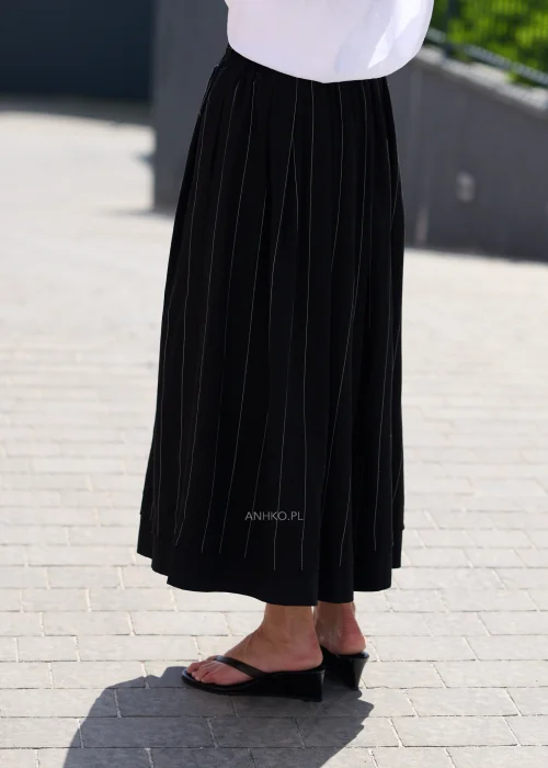 Czarna spódnica maxi z delikatnymi pionowymi prążkami i elastyczną talią, zwiewny fason w eleganckiej minimalistycznej stylizacji.